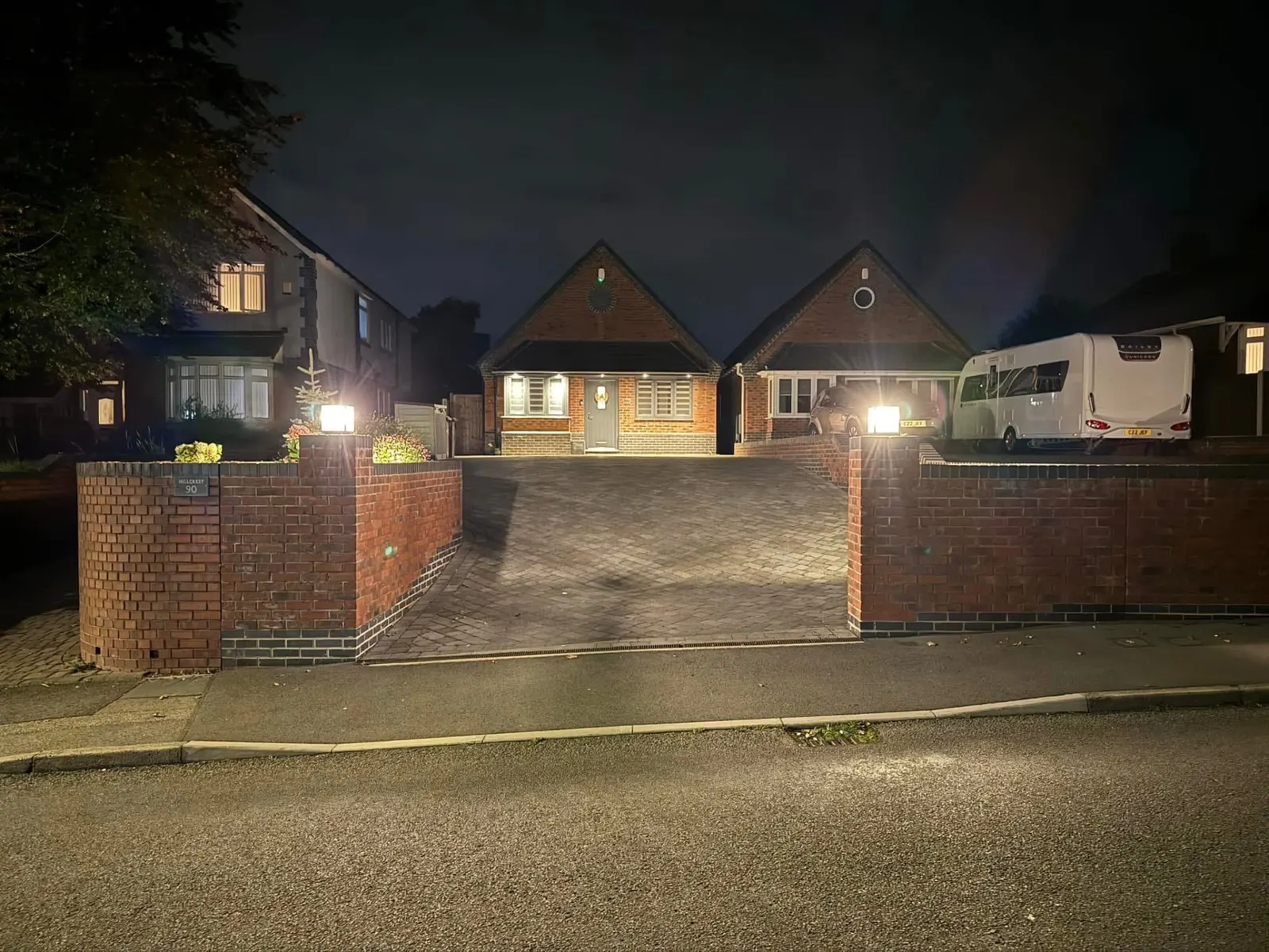 Rewired bungalow at night with new exterior floodlighting, porch lights and driveway lighting installed by Stret Limited electricians