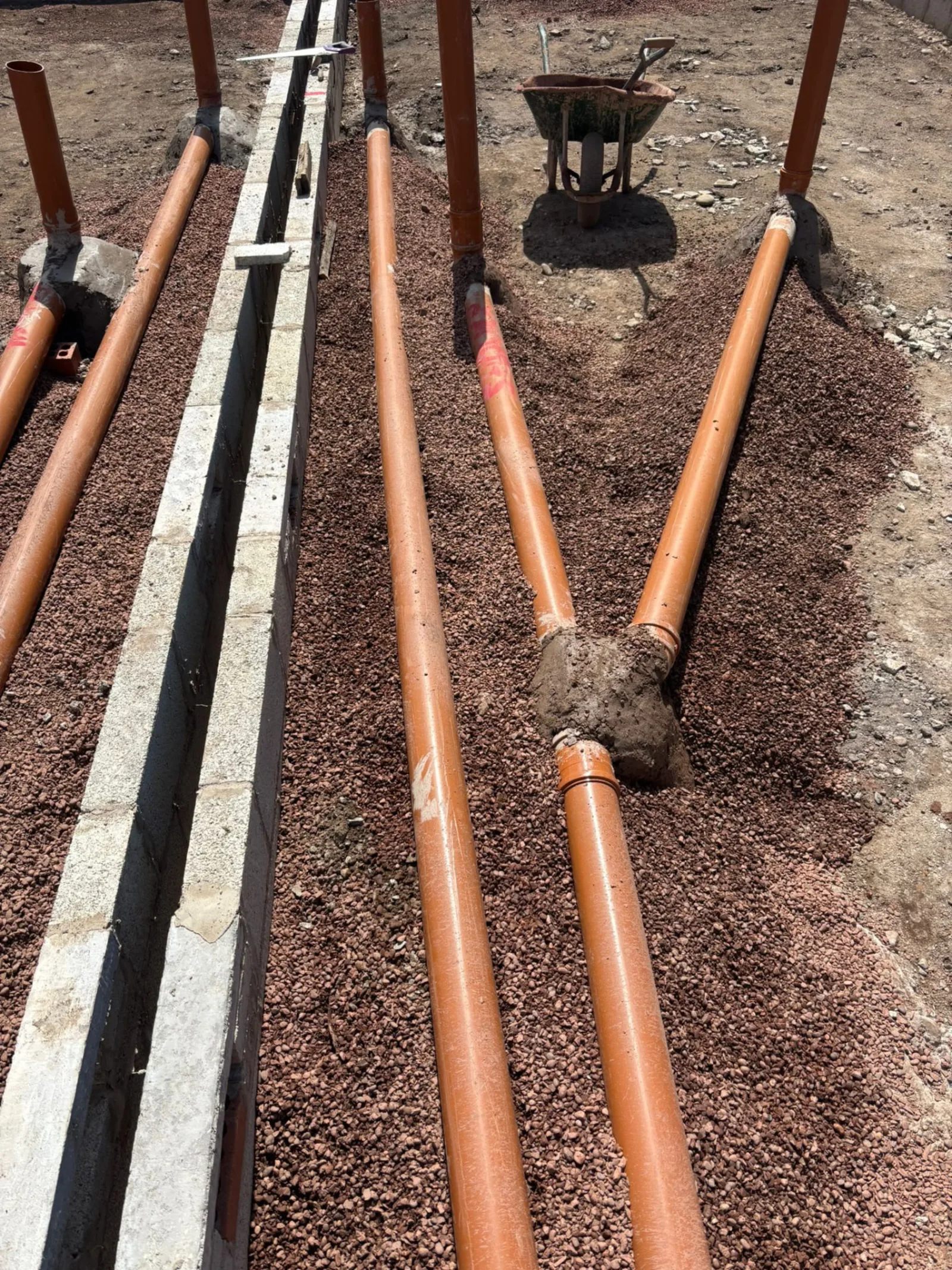New foul and surface water drainage runs laid on pea gravel bedding beside strip foundations on a Stret Limited groundworks site