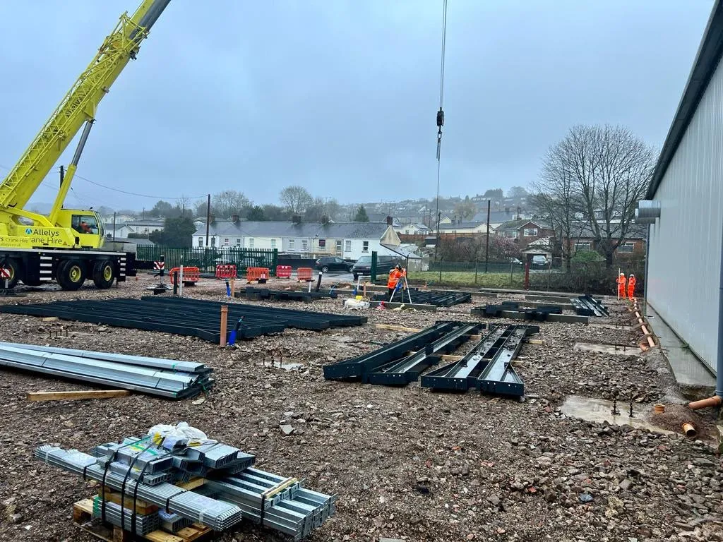 Crane lifting steel frame sections into place on a commercial construction site