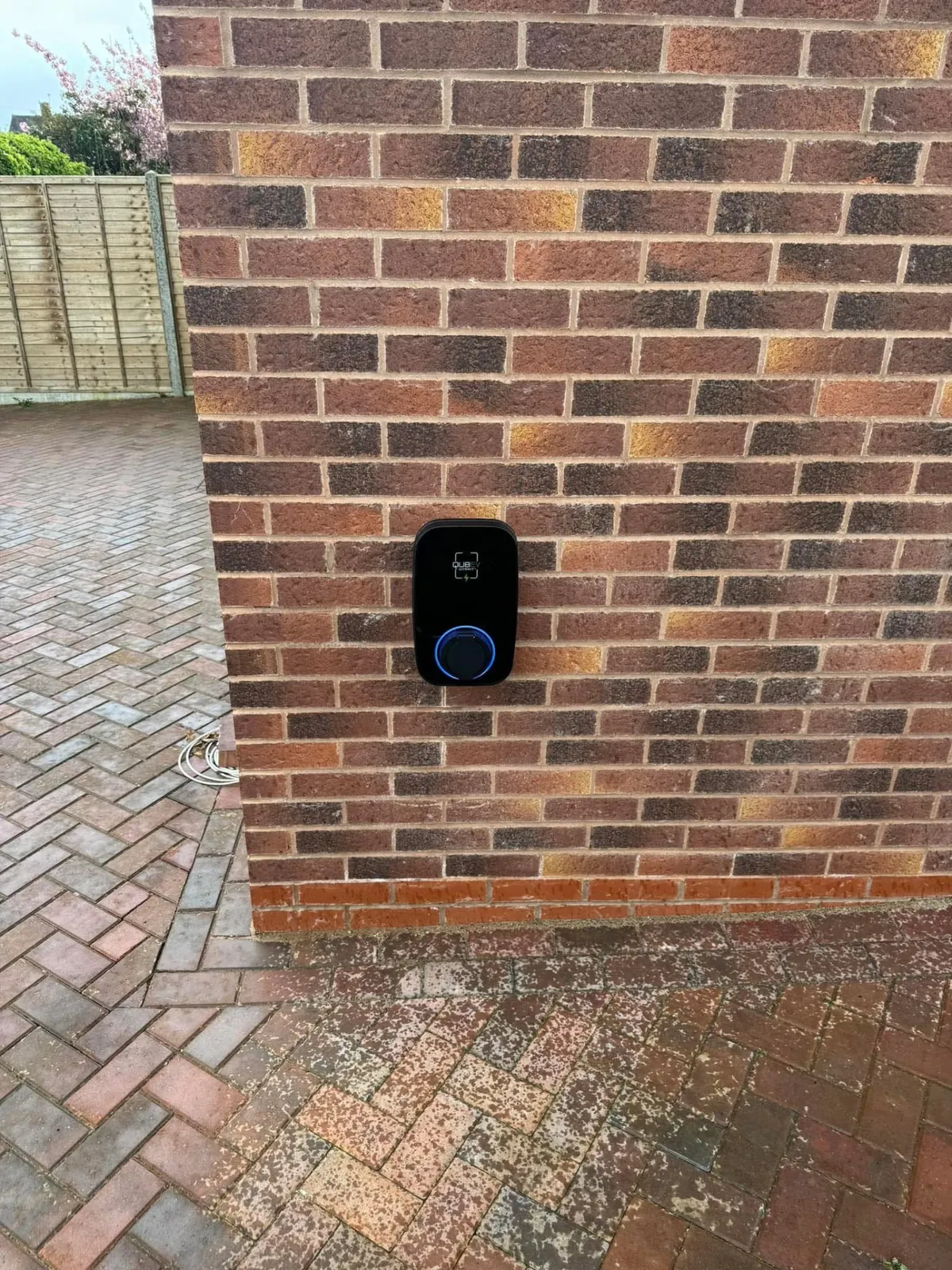 Home EV charger installation on a brick wall beside a driveway, installed and certified by Stret Limited