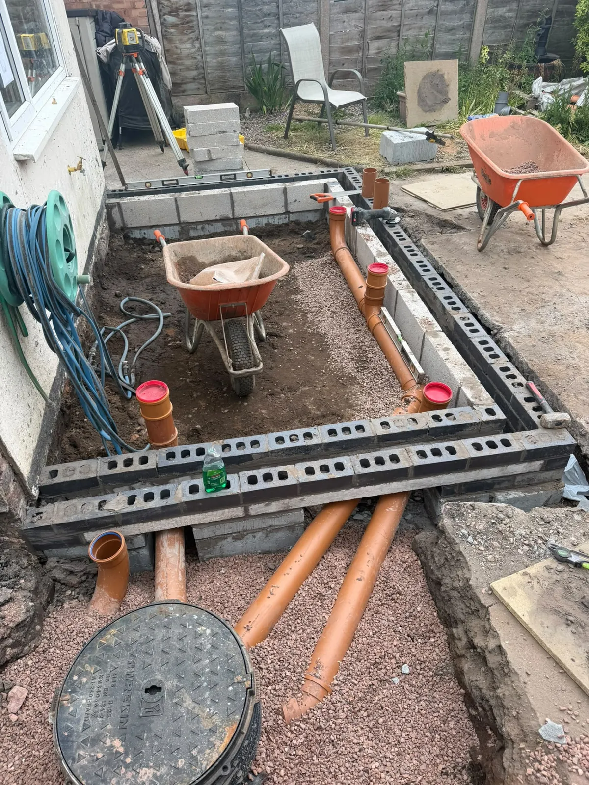 Extension foundation trench with drainage pipework and blockwork built up to damp course
