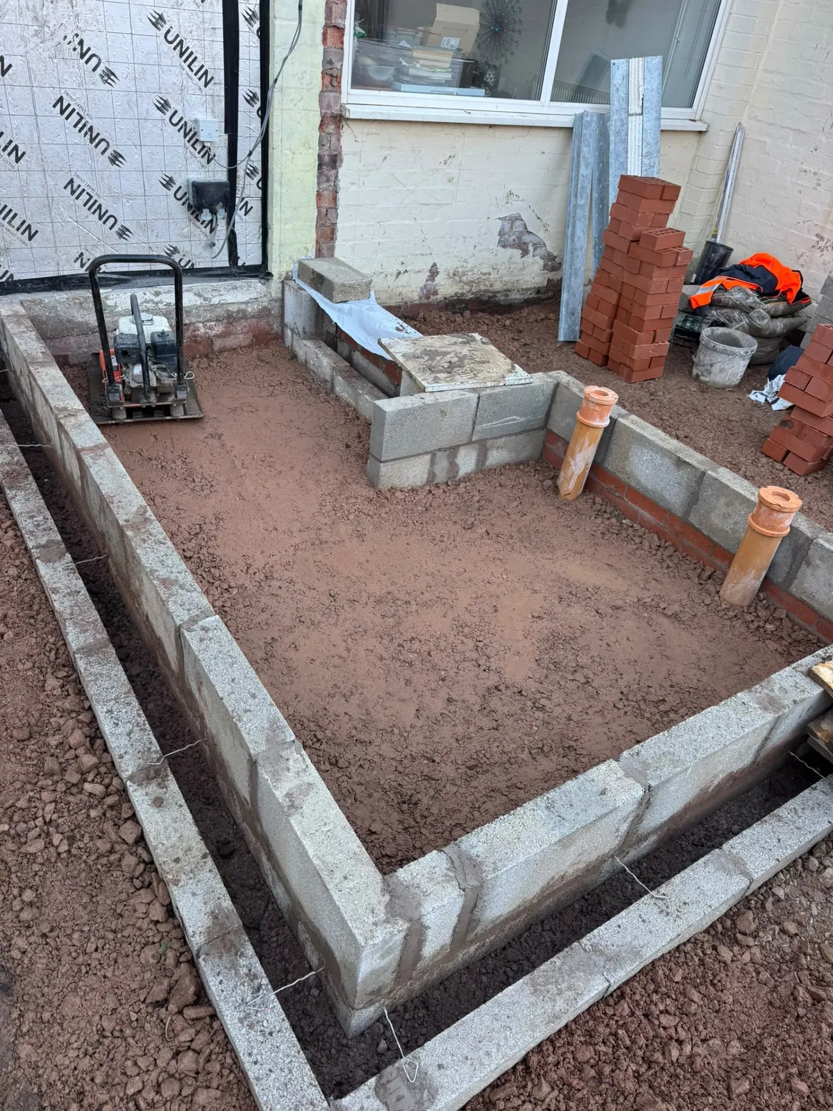 Extension foundations with compacted base, blockwork and drainage fittings ready for the slab