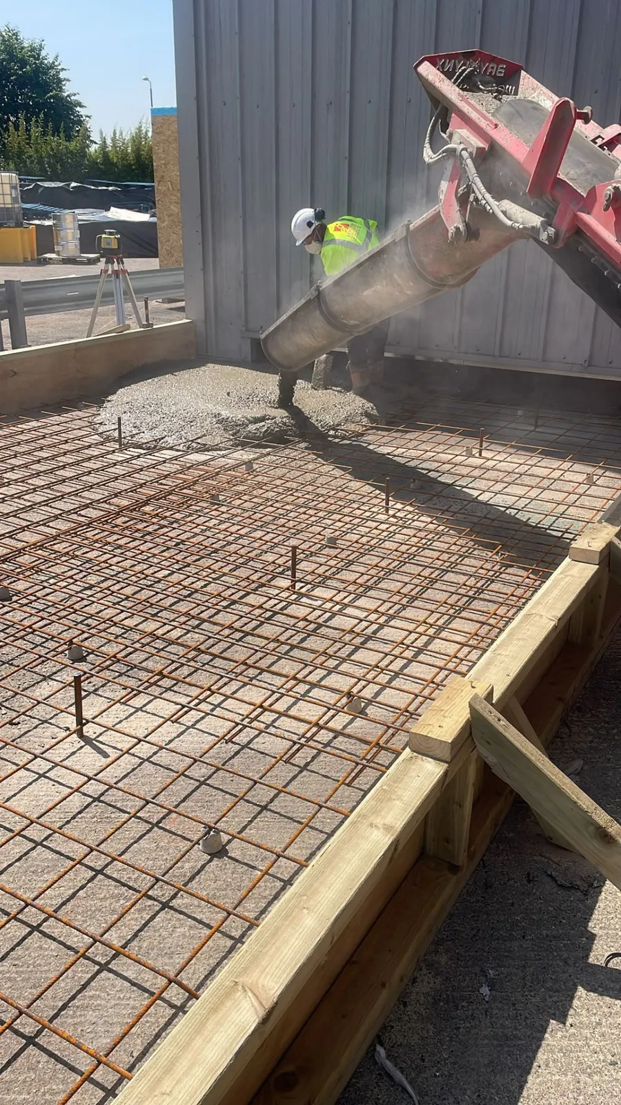 Concrete being poured over reinforcement mesh for a new slab